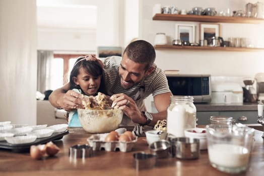 Shot of a father teaching his daughter how to bake in the kitchen at home