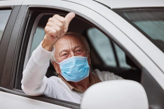 Thumbs up for getting vaccinated. Shot of a senior man showing a thumbs up in his car at a drive through vaccination site.