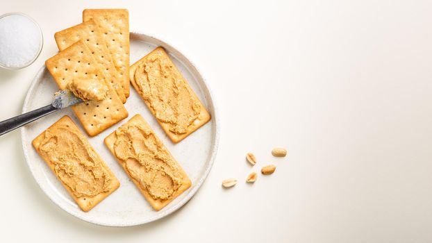 Peanut butter spread on soda crackers on the plate