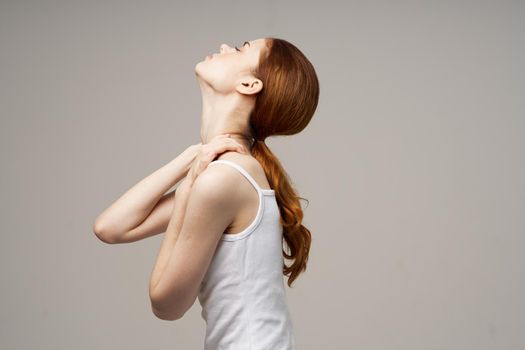 woman in white t-shirt rheumatism pain in the neck health problems light background