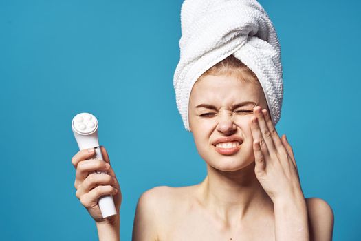 woman with bare shoulders with a towel on her head facial massager care