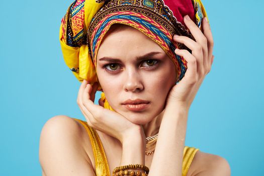pretty woman in multicolored turban attractive look Jewelry smile blue background