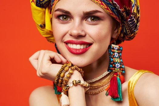 pretty woman in multicolored turban attractive look Jewelry red background