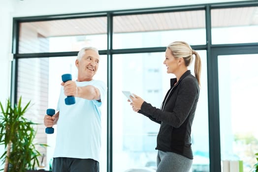 I'm impressed with your progress. Shot of a physiotherapists helping her senior patient with his exercises in a fitness center.