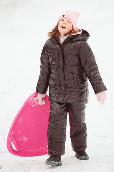 Active girl sliding down the hill. Happy child having fun outdoors in winter on sledge. Family time.