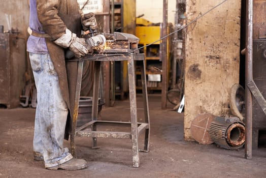 Where industrial meets creative.... A man grinding a piece of metal in a workshop.