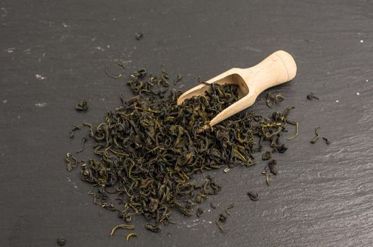 green tea in vintage spoons on dark wooden background with copyspace