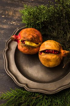 Ripe organic pomegranate fruits on bright plates on dark rustic wooden table