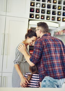 Bound together by love. Shot of a husband lovingly kissing his wife in the kitchen with his family.