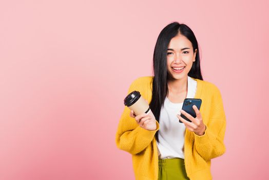 Happy Asian portrait beautiful cute young woman excited smiling holding mobile phone and coffee to go