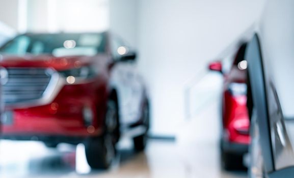 Blur new red car parked in luxury showroom. Car dealership office. New car parked in modern showroom for sale and rental service. Automobile leasing agent and car dealer center concept. EV market.