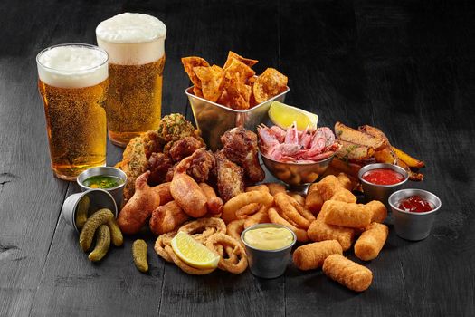 Beer set of savory snacks with sauces, pickles and lemon