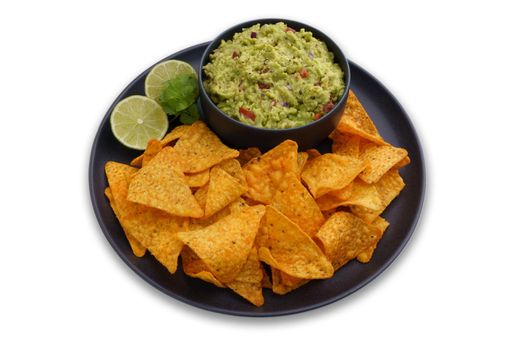 Black plate of guacamole dip and tortilla chips or nachos isolated on a white background