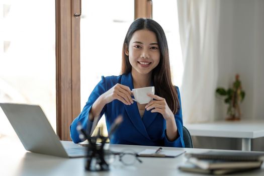 Portrait of smiling asian businesswoman working with laptop at her office