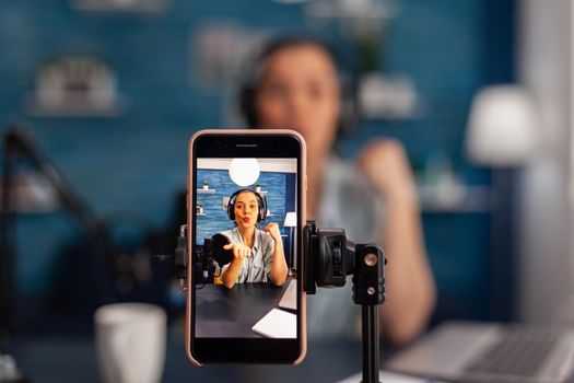 Closeup of smartphone recording woman influencer on live stream podcast.
