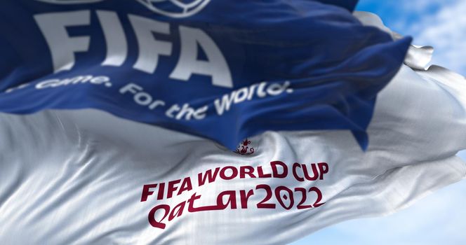Doha, Qatar, January 2022: Flags with FIFA and Qatar 2022 World Cup logo waving in the wind