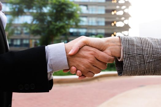 Business man and woman shake hands outside office buildings. Handshake.