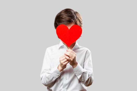 Boy covering his face with red st valentines heart