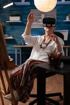 Retired artist using virtual reality goggles to visualize 3d model for inspiration before sketching