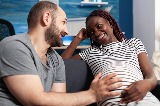Happy pregnant multiethnic young couple smiling at each other