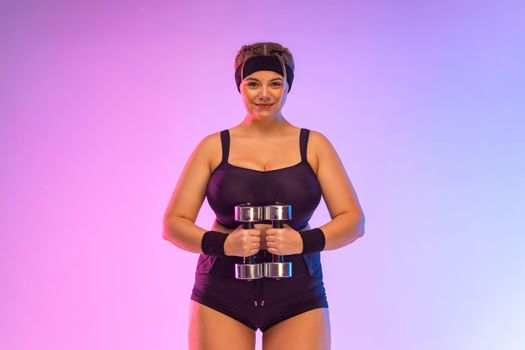 Young fat woman sportswoman. Body positive fitness. The girl wants to lose weight with dumbbells. Photo for advertising design for weight loss products and fitness equipment.