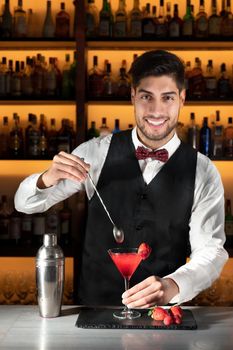 Young barman serving a cocktail at night club.