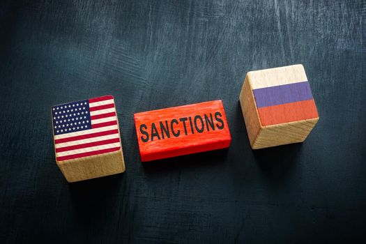 Wooden cubes and flags of USA and Russia and word sanctions.