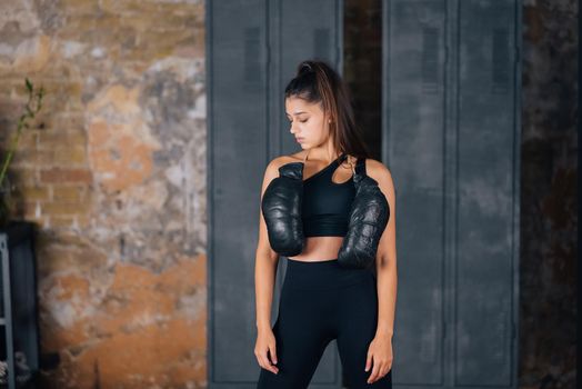 Sporty woman in sportswear posing on camera with boxing gloves.