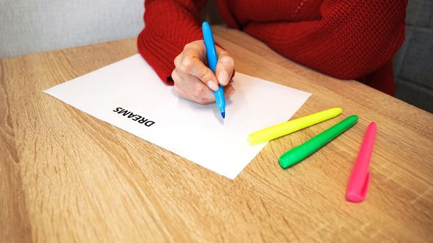 Woman writing down her dreams list by colored markers
