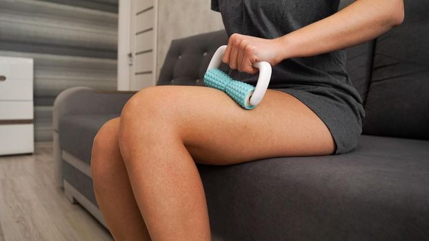 A woman uses a massage roller to massage her legs. Massage for elastic skin