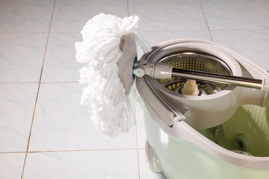 Mop with microfiber head spinning on the bucket