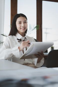 Asian Businesswoman or Accountant hands holding paperwork with calculator, account and saving concept.