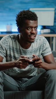Black man using controller and console to play video games