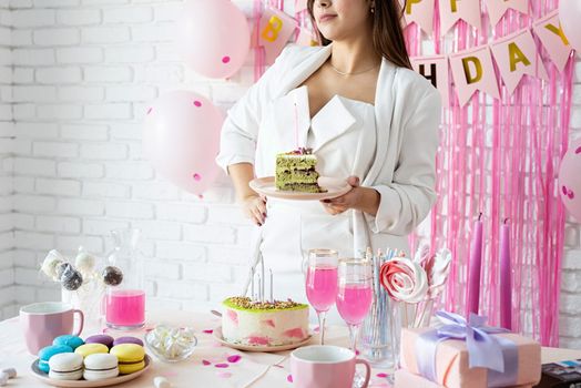 Beautiful woman celebrating birthday party holding a piece of cake making wish