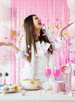 Beautiful woman celebrating birthday party throwing pink confetti
