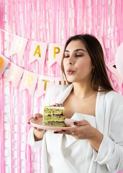Beautiful woman celebrating birthday party holding a piece of cake making wish