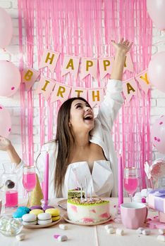 Beautiful excited woman celebrating birthday party throwing pink confetti