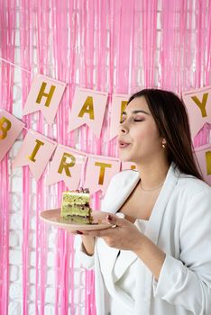 Beautiful excited woman celebrating birthday holding cake making wish