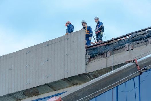 Moscow,Russia,05,10,2021:Restoration,reconstruction and repair of the building.Construction workers in hard hats install concrete slabs on the roof of the structure.Housing Restoration Construction
