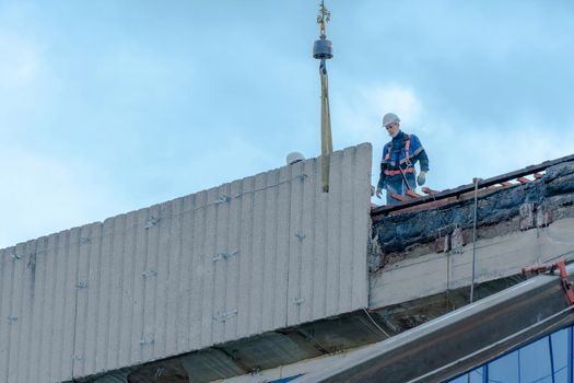 Moscow,Russia,05,10,2021:Restoration,reconstruction and repair of the building.Construction workers in hard hats install concrete slabs on the roof of the structure.Housing Restoration Construction