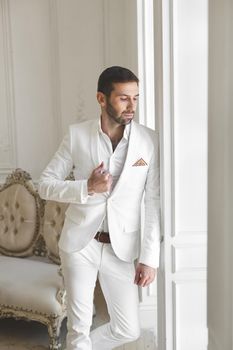 Elegant man with a beard in a white classic suit.