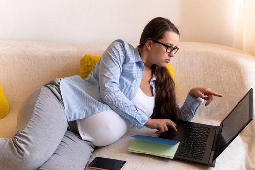 Successful hardworking Pregnant business Woman With Laptop and Noutbook. Young Ledy In Pregnancy Work conducts an online conference lesson Remotely Using Technology At Home. Maternity leave Concept