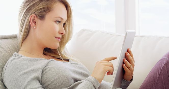 Connectivity at your fingertips. Shot of a pregnant woman using a tablet at home.