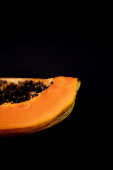 Half of fresh papaya laying down on black surface