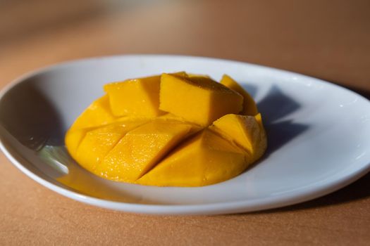 Diced mango on white plate above brown table