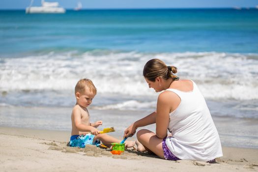 mother and son build sand castle on the beach.