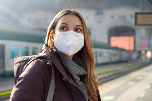 Portrait of casual woman waiting train with KN95 FFP2 protective mask at train station on winter