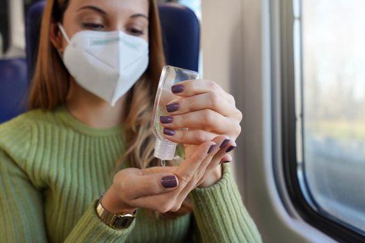 Business woman with medical face mask using alcohol gel sanitizer hands on public transport. Antiseptic, hygiene and health care concept. Focus on hand with alcohol gel bottle.