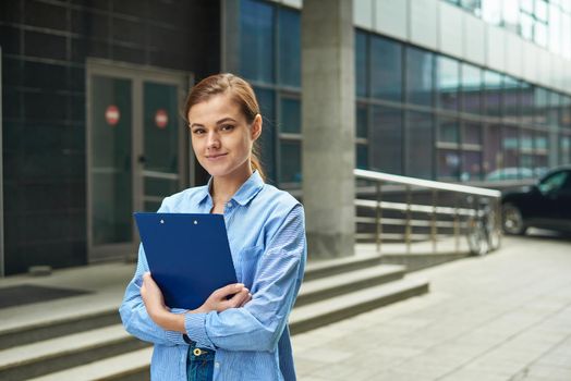 Young female businesswoman holding a tablet with documents at hand and looking at the camera, smiling. The concept of working in the office of young professionals