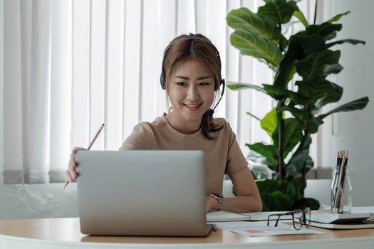 Portrait of smiling beautiful young business woman with headphones working in modern office desk using computer, Business people employee freelance online marketing e-commerce telemarketing concept